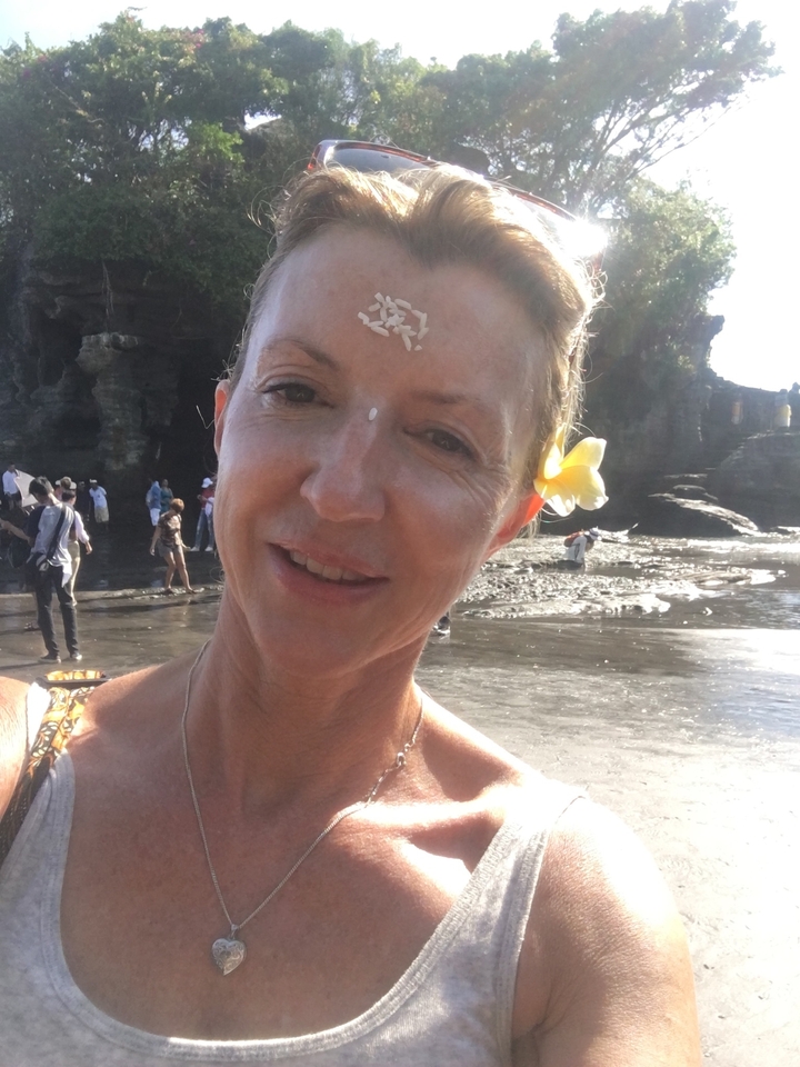 Close-up of a woman with a flower in her hair at a beach.