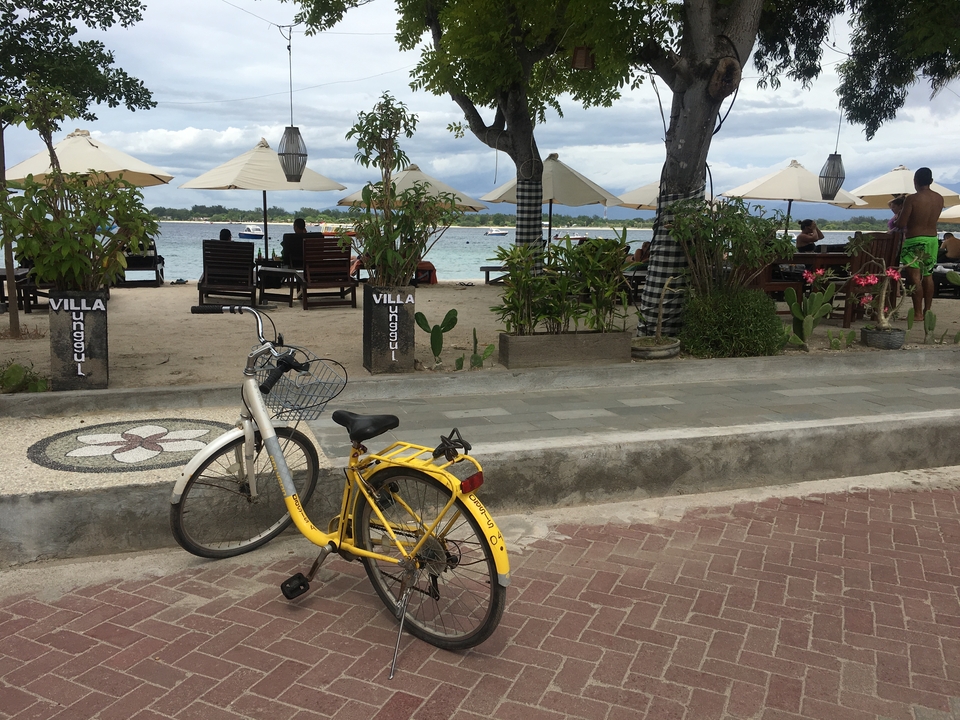 Bicycle on a paved path beside a beach.