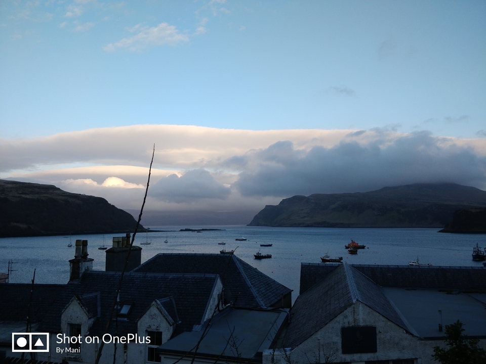 Calm bay with boats and mountains in the distance.