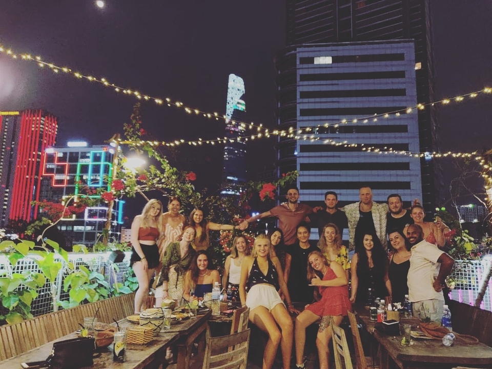 Group of people on a rooftop at night with lights.