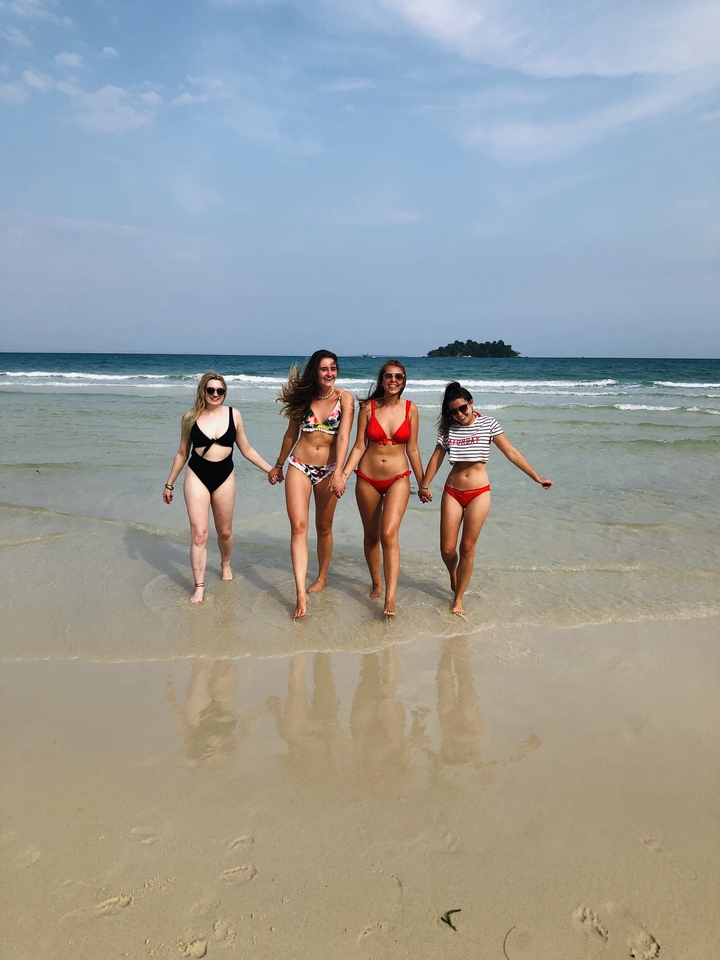 Four people walking in the sea.