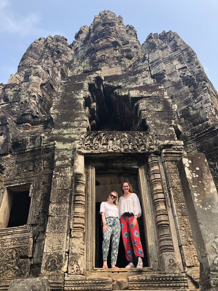 Two people posing in front of ancient stone ruins.