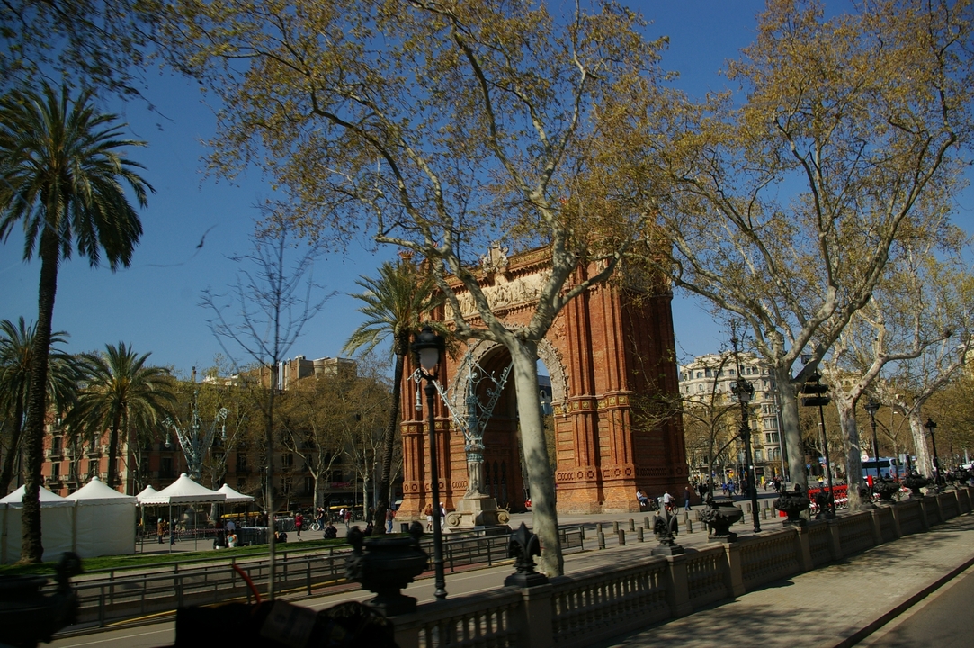 Arch monument surrounded by trees and people.