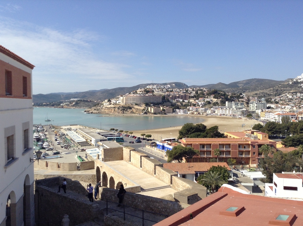 View of a coastal town with a sandy beach and parked boats.