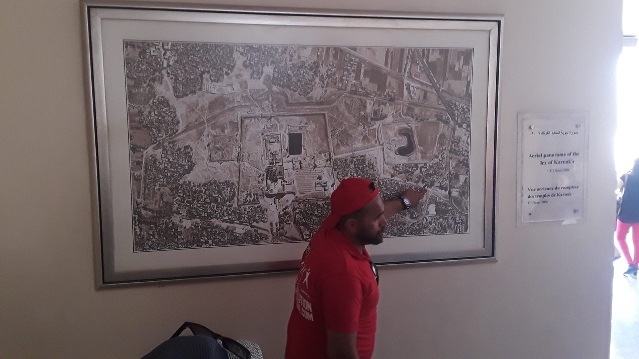Person pointing at a framed map on the wall.