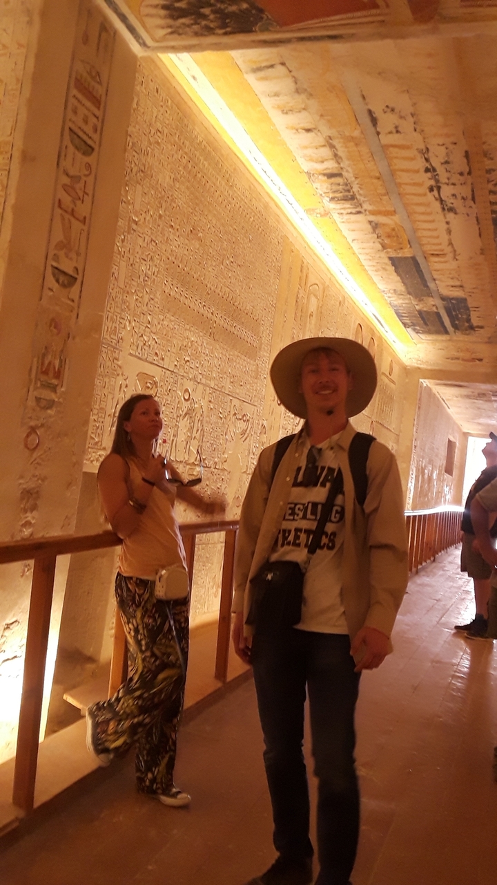 Visitors inside a tomb with wall carvings.