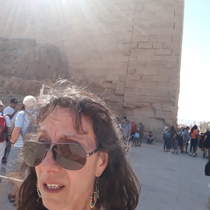 Woman in sunglasses with an ancient structure in background.