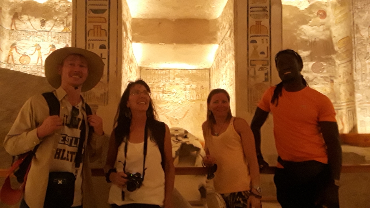Group of people posing happily in an ancient carved room.