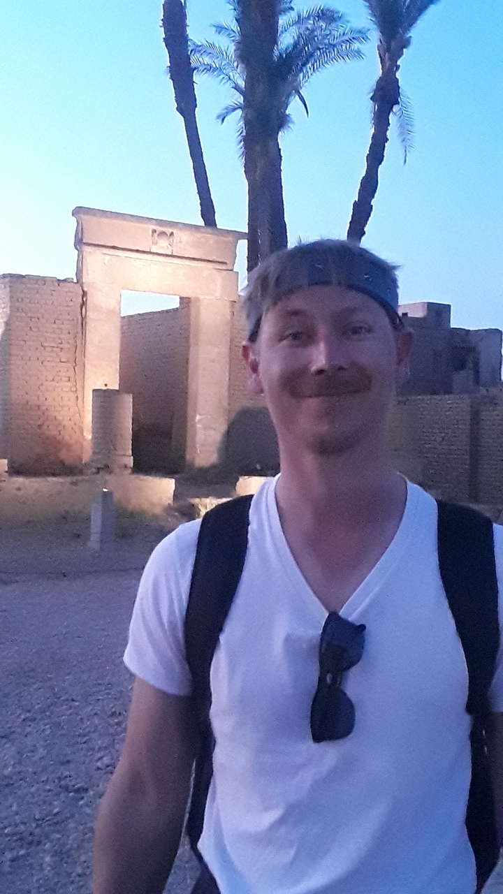 Man smiling with ancient walls as background.