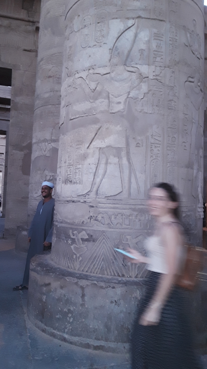 Blurred image of a person near an ancient carved column.