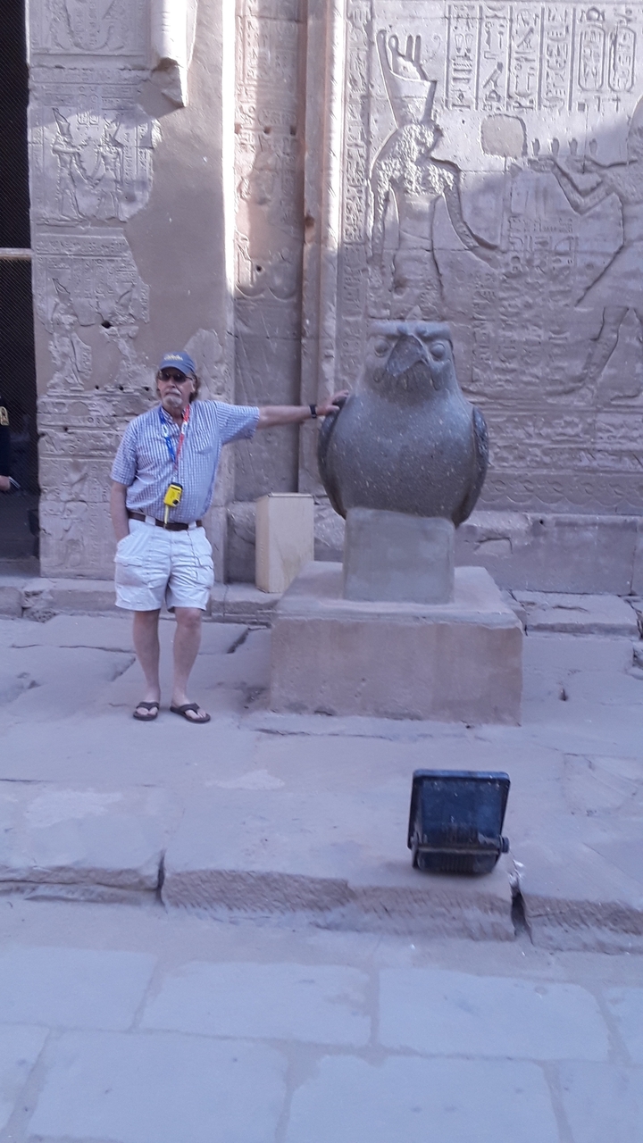 Man posing beside an ancient statue in a temple.