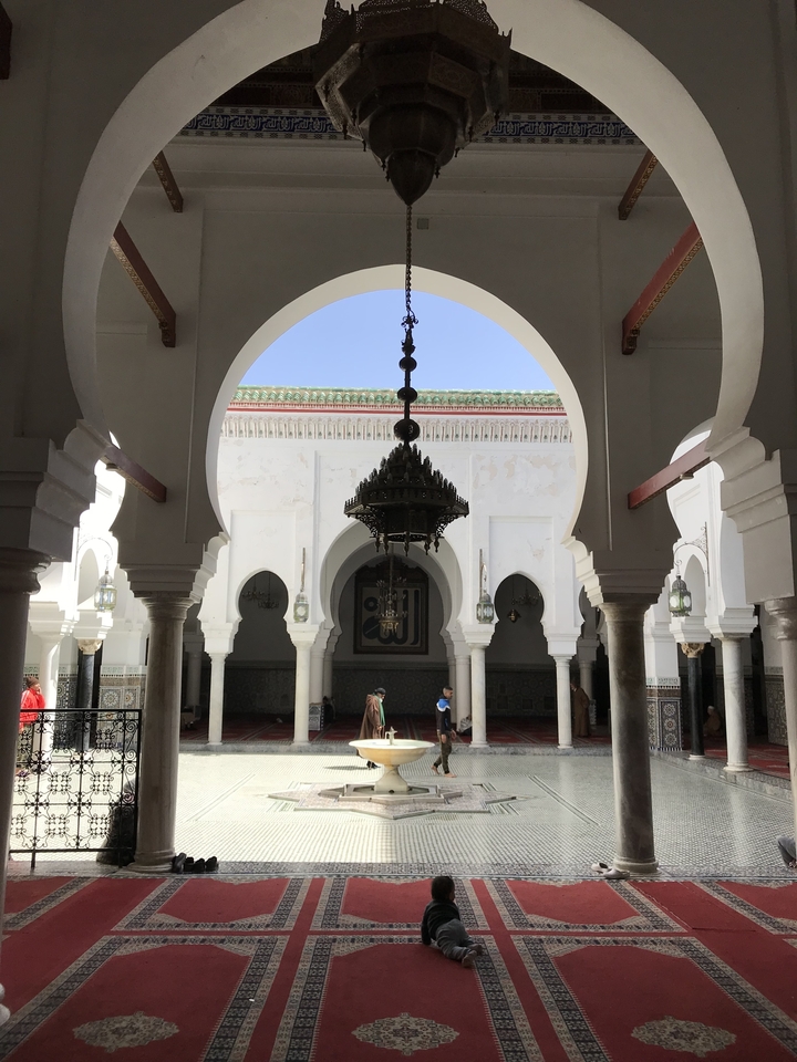 Intricate Islamic architecture with arches and a central chandelier.