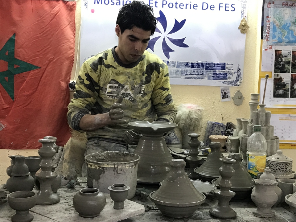 Man sculpting clay pottery in a workshop.