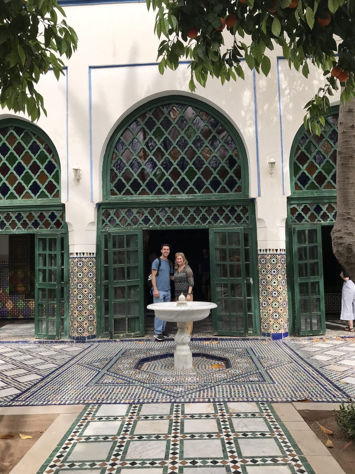 Two people standing in front of a traditional building with mosaic tiles.