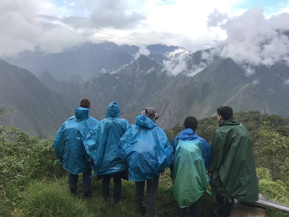 People wearing rain ponchos overlooking a mountainous landscape.