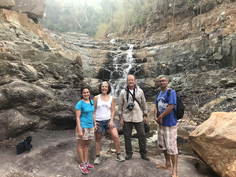 Groupe de personnes posant devant une petite cascade.