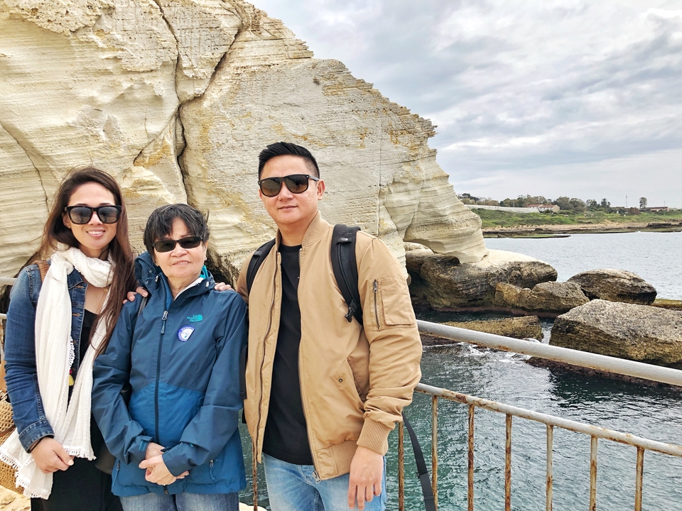 Family posing at a limestone cliff by the sea.