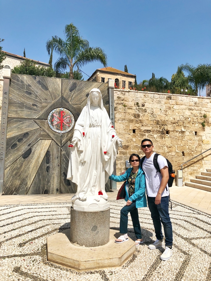 Two people posing next to a religious statue.