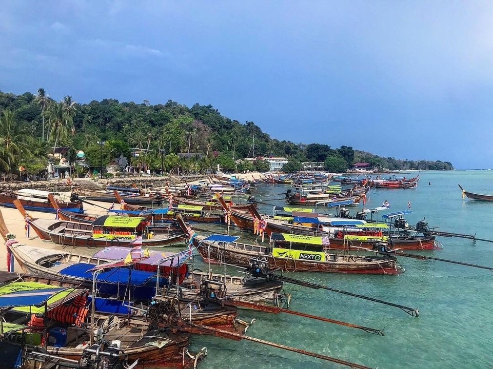 Line of traditional long-tail boats along a beach.