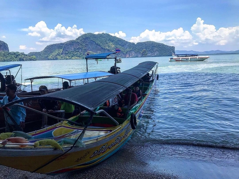 Long-tail boats on a clear blue sea with lush scenery in the background.