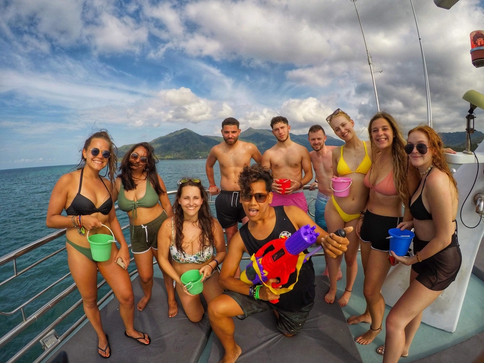 Group of friends on a boat holding water buckets, enjoying a sunny day.