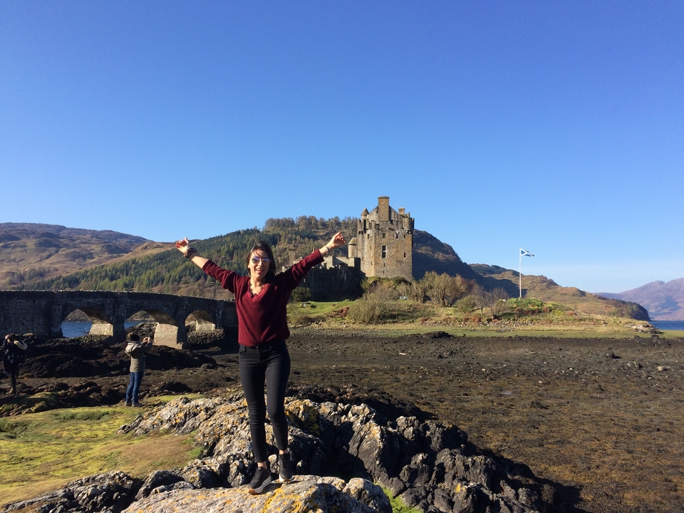 Person with arms raised in front of Eilean Donan Castle.
