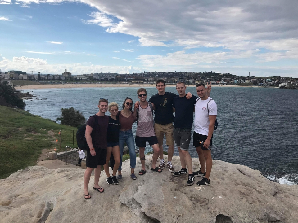Friends posing on a cliff with Bondi Beach in the background.