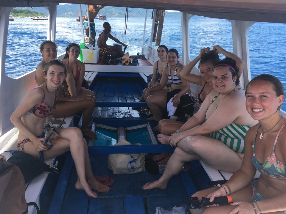 Group of friends on a boat in the ocean, smiling for a photo.