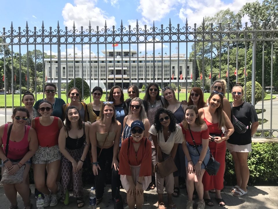A group of people posing in front of a landmark building with a metal fence.