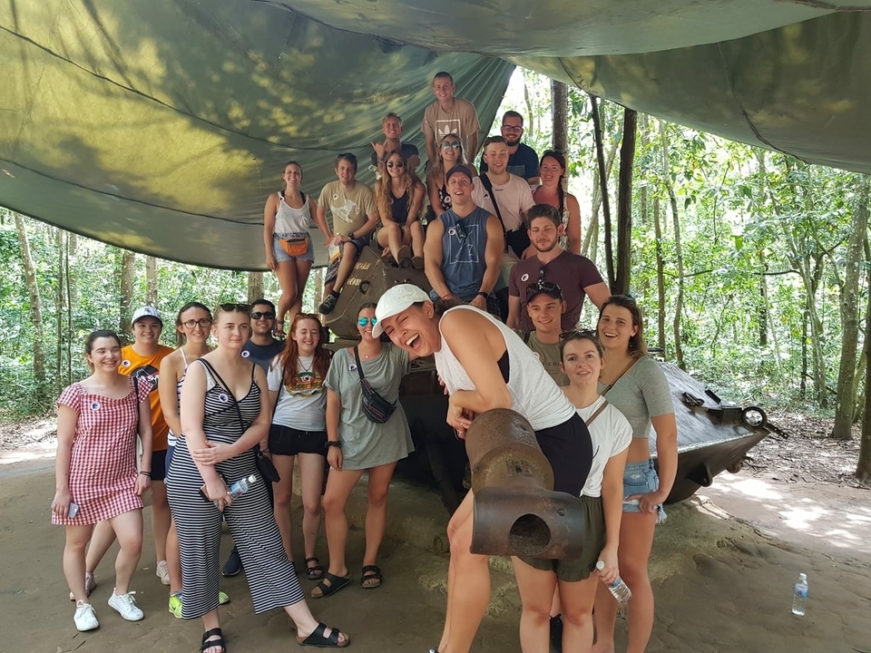 Large group of people around a tank, with a forested backdrop.
