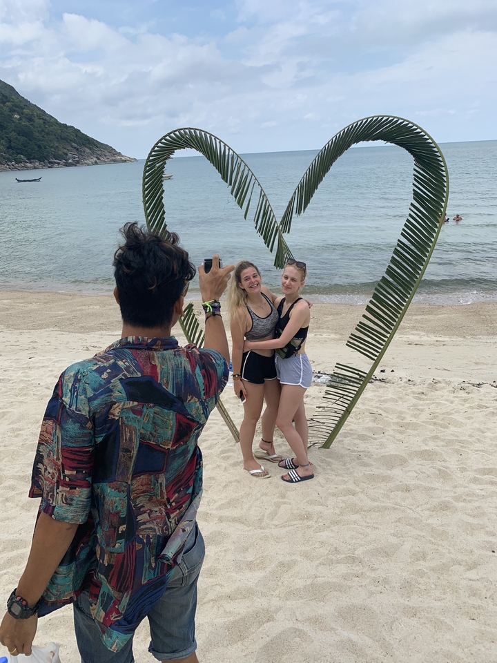Person taking a photo of two friends on the beach.