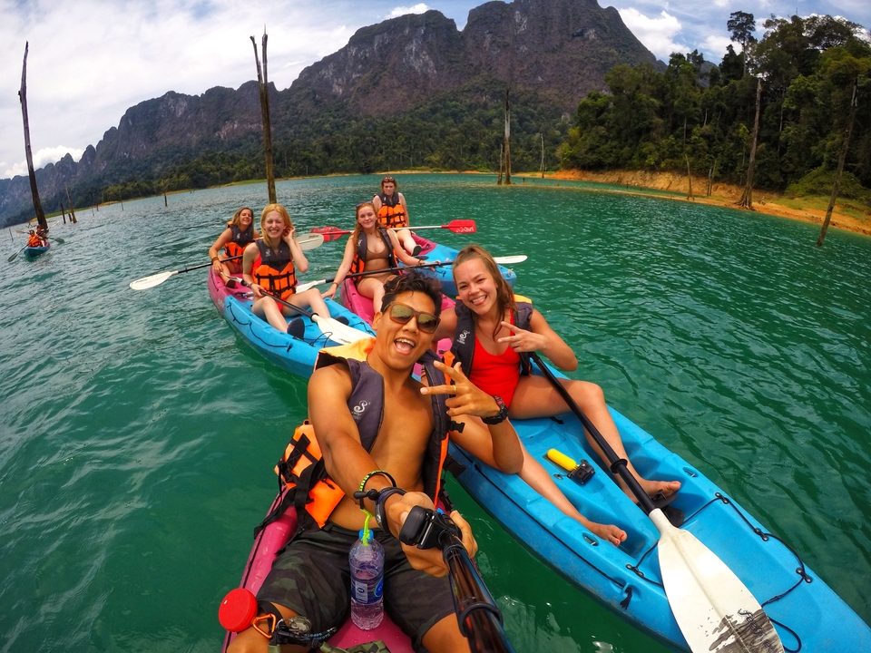 Group of kayakers having fun with scenic green water and mountains.