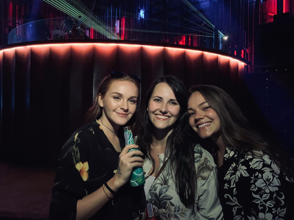 Three women smiling inside a dimly lit venue.