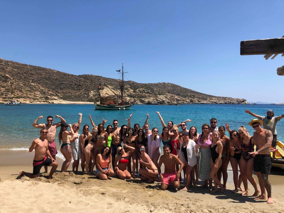 Group of people posing on a beach with a boat and mountains