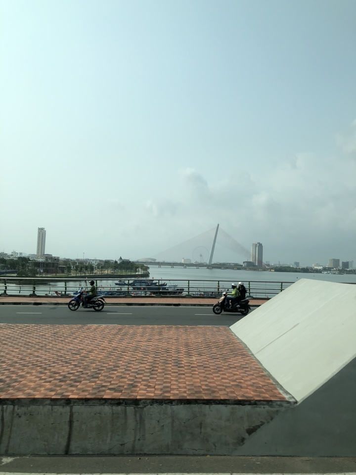 Bridge over a river with buildings and a Ferris wheel in the background.
