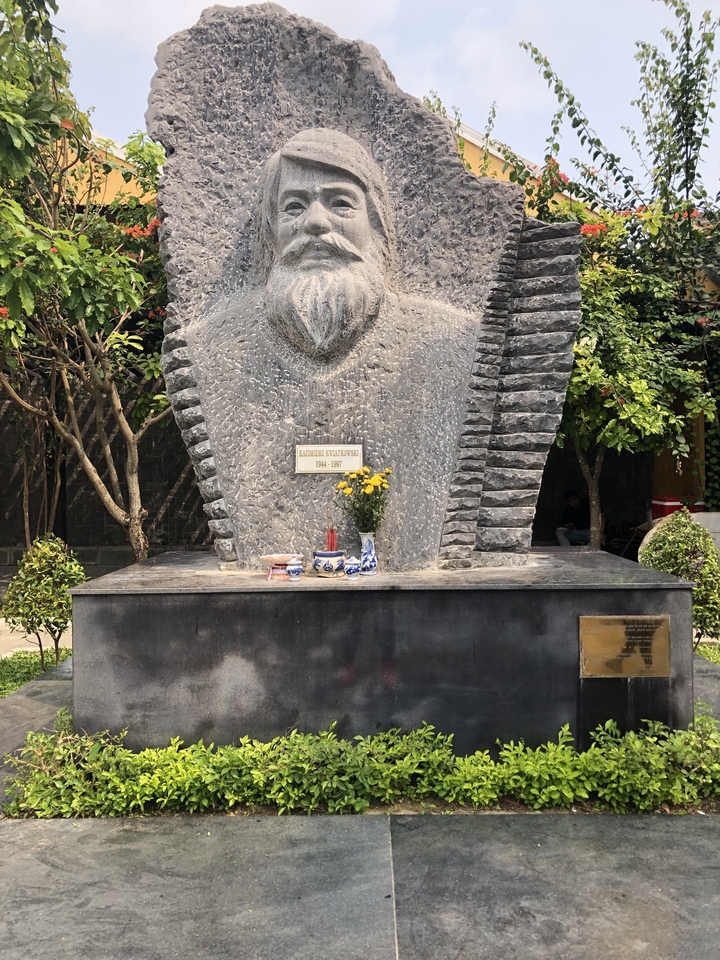Close-up of a stone monument with a plaque and flowers.