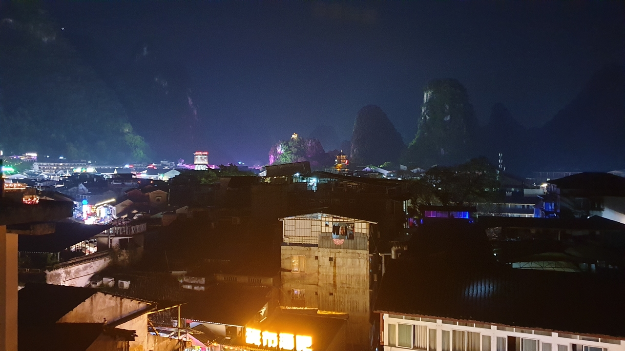Vue nocturne d'une ville avec des collines et des maisons illuminées.