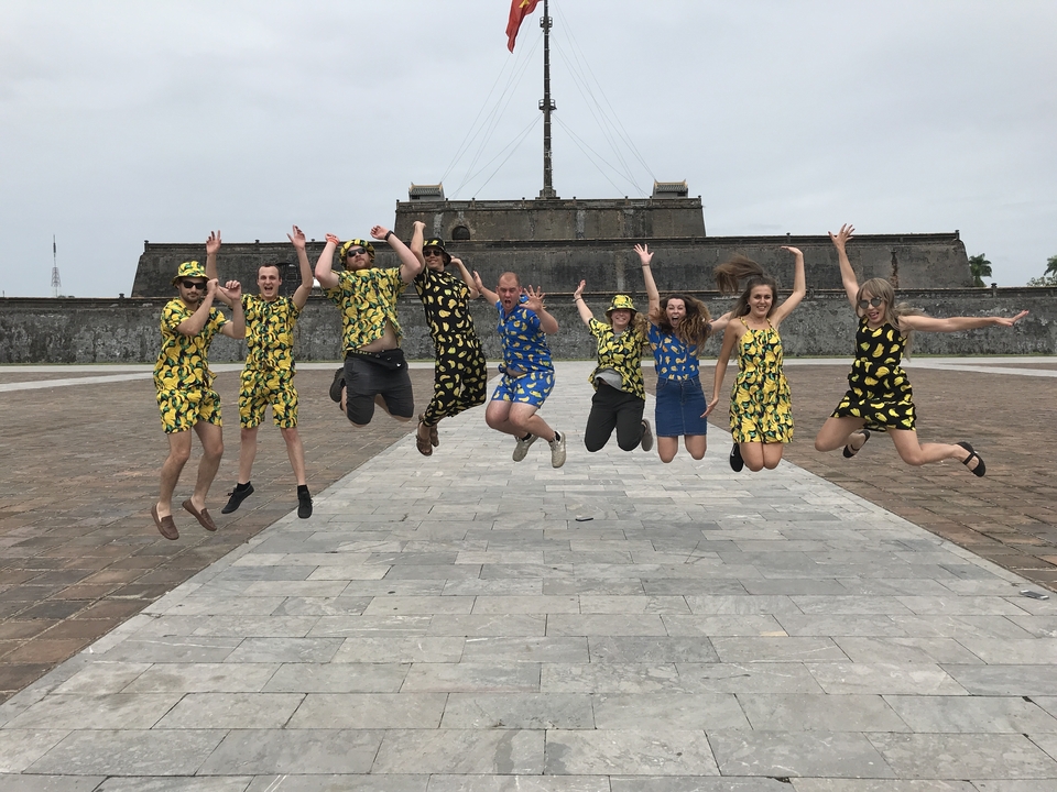 Group jump shot in matching outfits with an ancient fortress in the background.