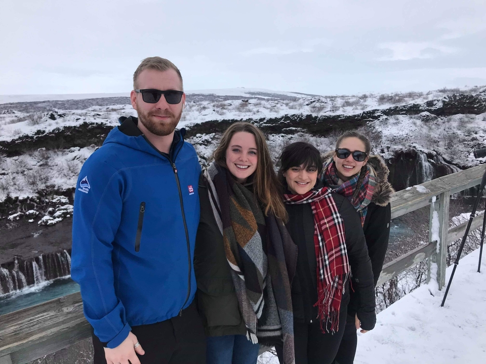 Group of people standing by a snowy landscape.