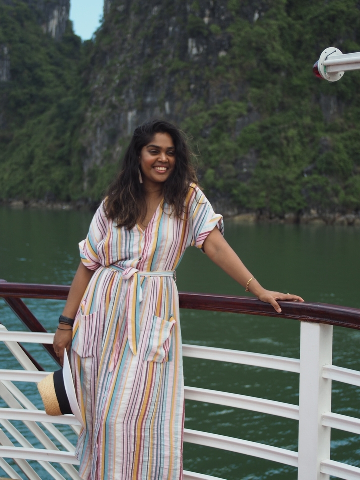 A smiling woman on a boat with cliffs in the background.