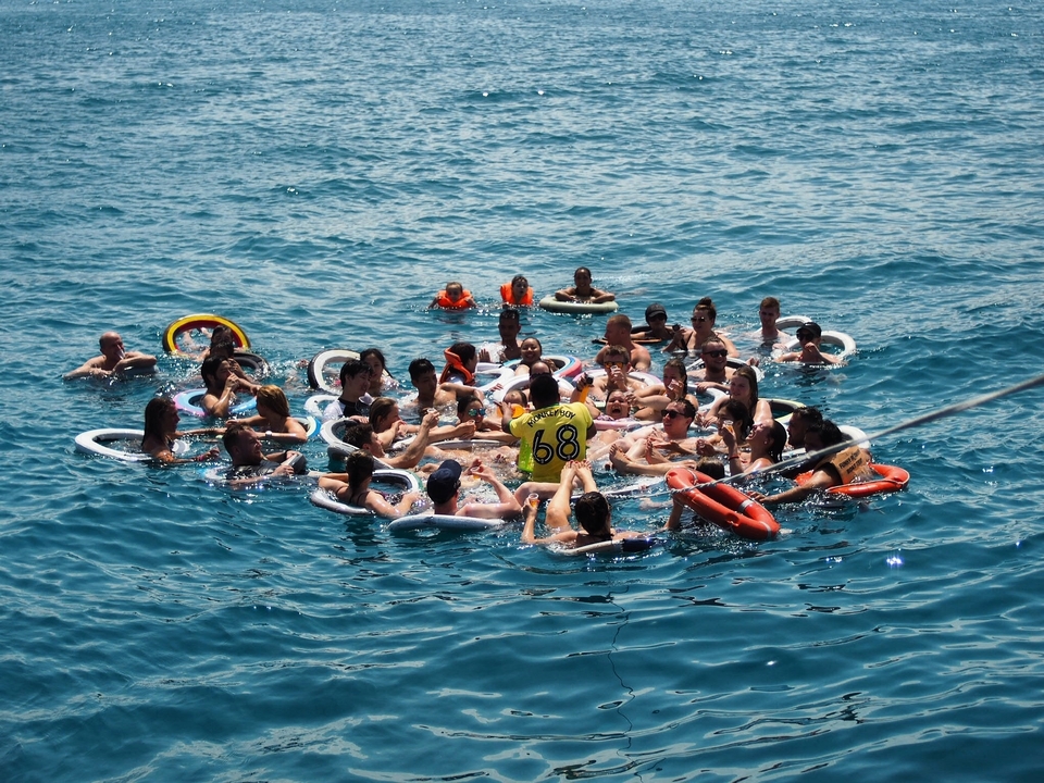 Large group of people floating with circular floats in the sea.