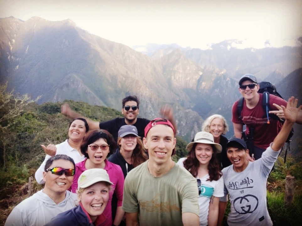 Group of hikers posing with mountains in the background.