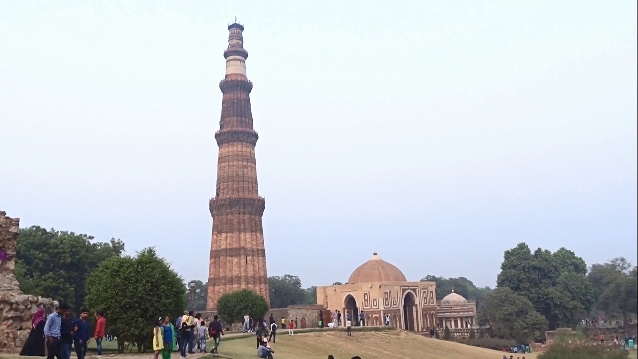 Tall historical tower and dome structure surrounded by people.