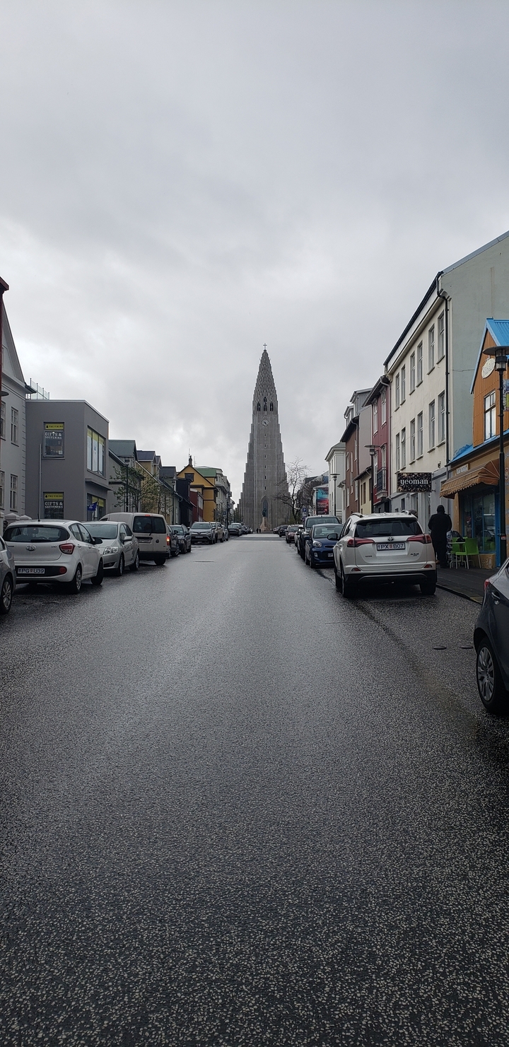 Street scene with cars and architecture leading to a prominent church.