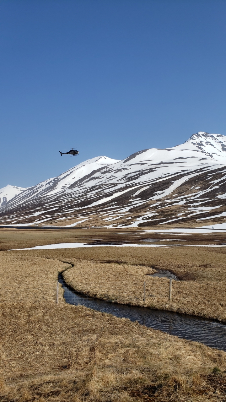 A helicopter flying over snow-covered mountains.