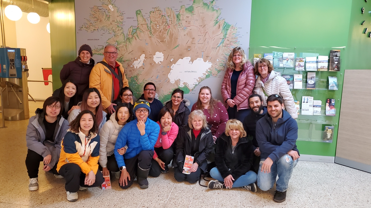 Group of tourists posing in front of a large map of Iceland.