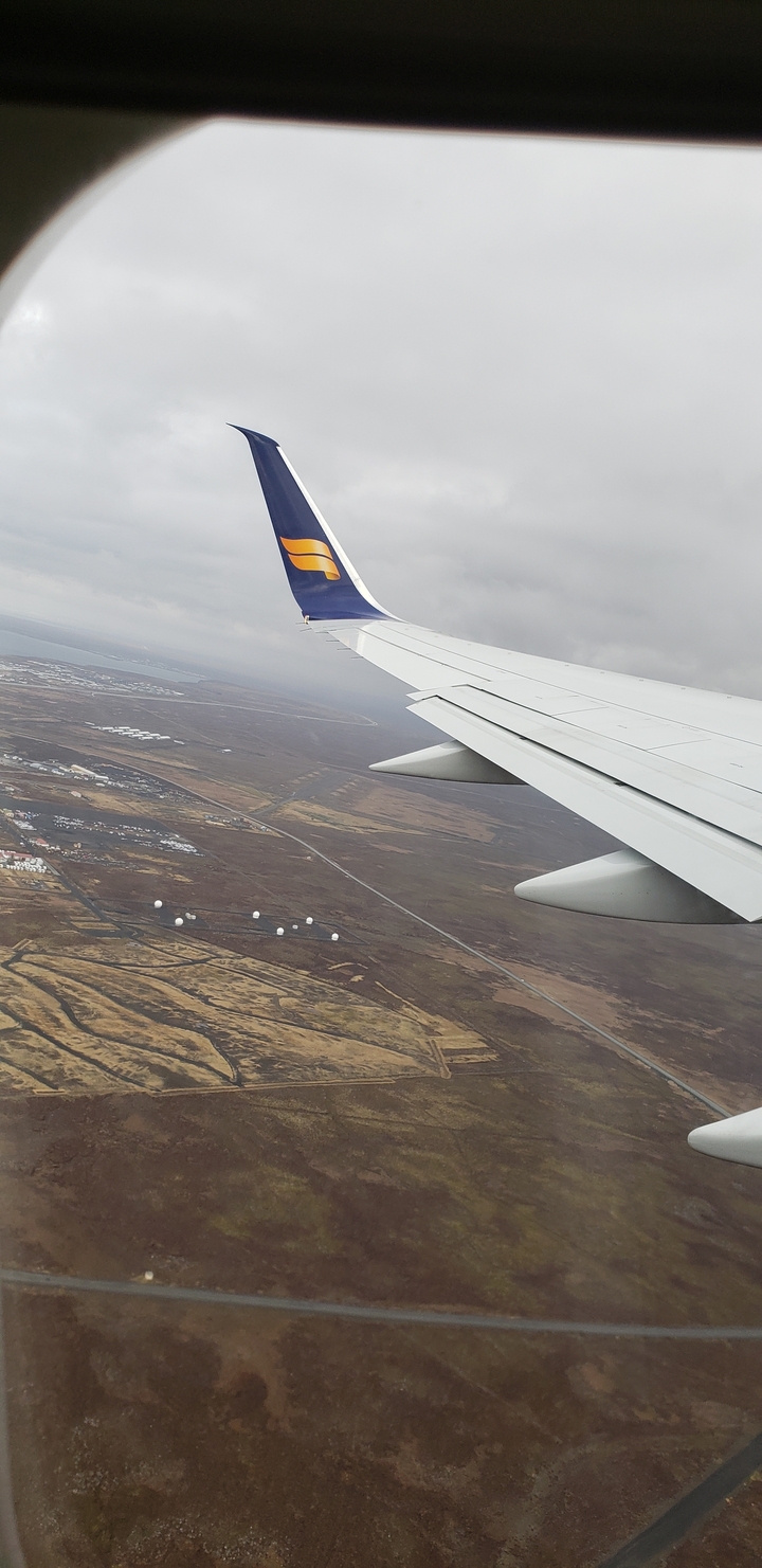 View from an airplane window showing the landscape below.