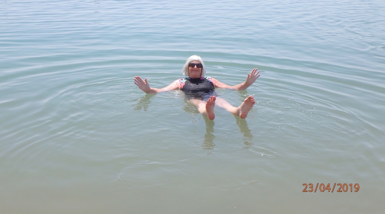 Personne flottant dans l'eau en souriant.