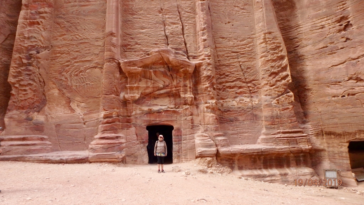 Personne debout devant une façade rocheuse sculptée.