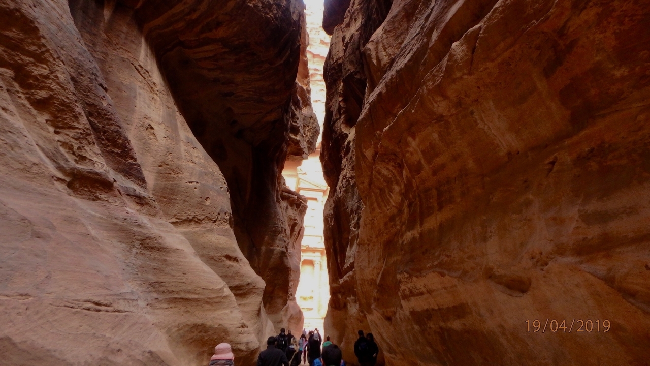 Des touristes marchant à travers un canyon étroit aux parois hautes.